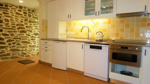 una cucina con elettrodomestici bianchi e un muro in pietra di Casa CÔA - Casas de Villar - Rural Experience a Vilar de Amargo