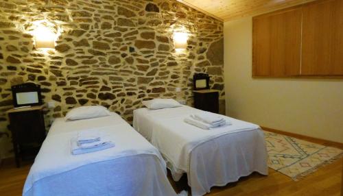 2 letti in una camera con parete in pietra di Casa CÔA - Casas de Villar - Rural Experience a Vilar de Amargo