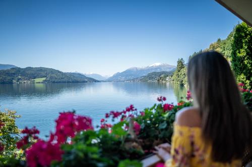 a woman looking out at a lake with flowers at Seefels Appartements in Döbriach