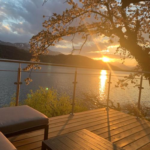 a sun setting over a lake with a wooden dock at Seefels Appartements in Döbriach