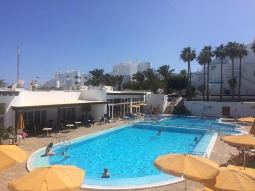 una gran piscina con sombrillas y gente en ella en Apartamentos Club Pocillos, en Puerto del Carmen