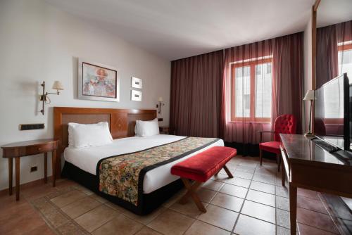 a hotel room with a bed and a desk at Exe Alfonso VIII in Plasencia