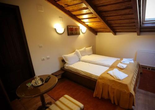 a bedroom with two beds and a table in it at Pensiunea Roua Muntelui in Brăzeşti