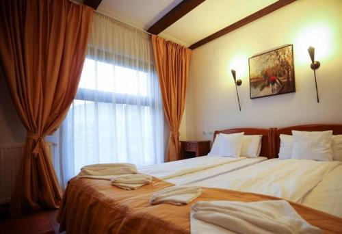 a hotel room with two beds and a window at Pensiunea Roua Muntelui in Brăzeşti