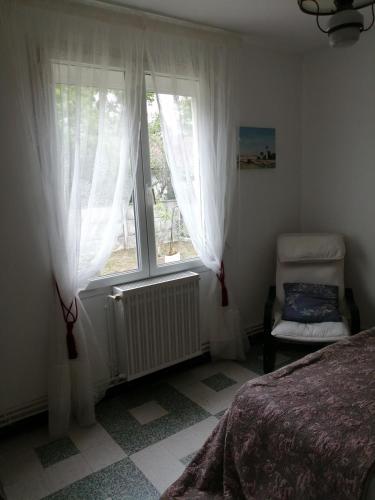 une chambre avec un lit, une fenêtre et une chaise dans l'établissement Villa l'bontemps, à Saint-Georges-de-Didonne