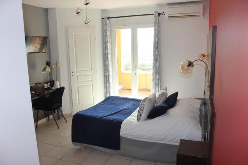 a bedroom with a bed and a desk and a window at The Originals City, Hôtel Côté Sud, Marseille Est in Allauch