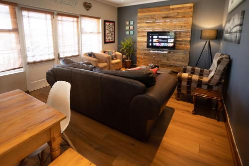 uma sala de estar com um sofá preto e uma mesa em Modern Shabby Chic Apartment em Durbanville