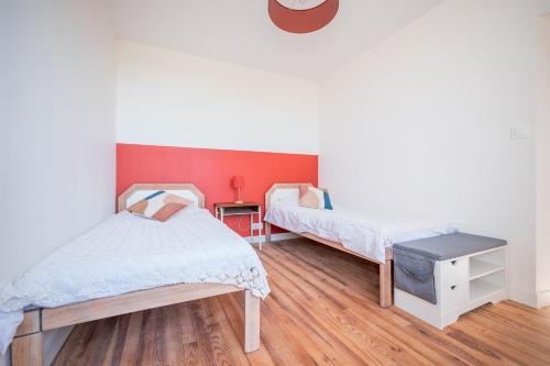 a bedroom with two beds and a red wall at Chambres et table d'hôtes - Les Jardins de la Longagne in Saussenac