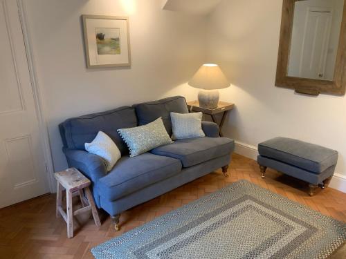 a living room with a blue couch and a stool at Masons Cottage, an Idyllic retreat in an area of outstanding beauty, close to Blenheim Palace, Oxford & The Cotswolds in Stonesfield