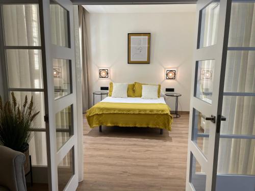 1 dormitorio con 1 cama con colcha amarilla en Suites Chinitas, en Málaga