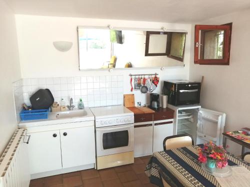 une petite cuisine avec des appareils électroménagers blancs et une table dans l'établissement T2 36 m2, RdC de villa, clim, gd jardin clos, animx ok, quartier Mt Faron très calme, wifi, parking, à Toulon