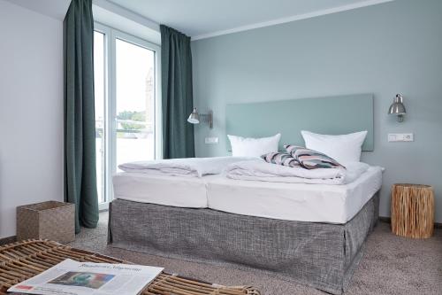 a bedroom with a large bed with a large window at Hotel Trabener Hof in Traben-Trarbach