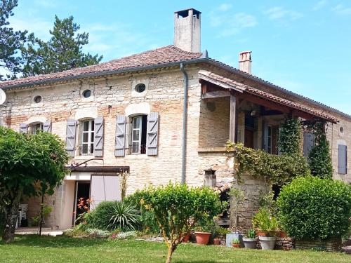 een oud bakstenen huis met planten in de tuin bij La maison du pech in Monteils