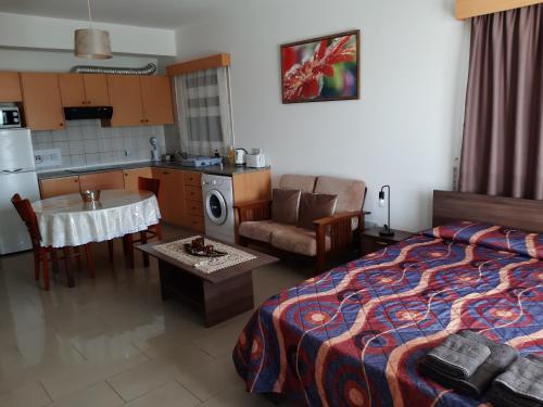 a bedroom with a bed and a kitchen and a table at Pari's Holiday apartments-Paphos in Paphos