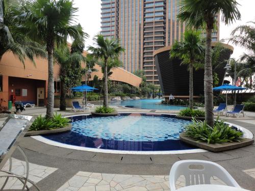 a large swimming pool with palm trees and chairs at Best Apartment at Times Square in Kuala Lumpur