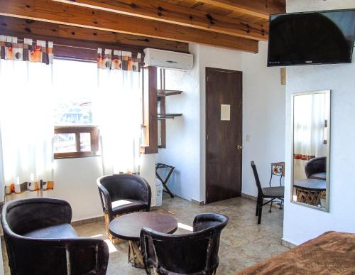 a room with chairs and a table and a tv at Ma Petite Maison in Tepoztlán