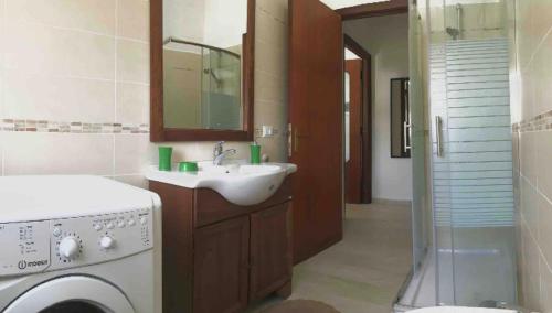 a bathroom with a sink and a washing machine at Pineta sul mare S'Ena e Sa Chitta in Santa Lucia