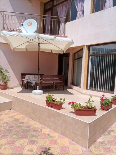 een patio met een tafel, een parasol en potplanten bij Villa Mars in Sunny Beach