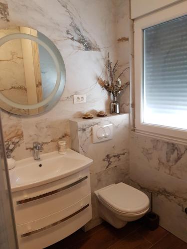 La salle de bains est pourvue d'un lavabo, de toilettes et d'un miroir. dans l'établissement apartman Amigo, à Kaštela