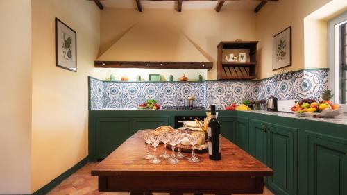 a kitchen with green cabinets and a wooden table with wine glasses at CASALE DELL'OASI 12, Emma Villas in Gallese