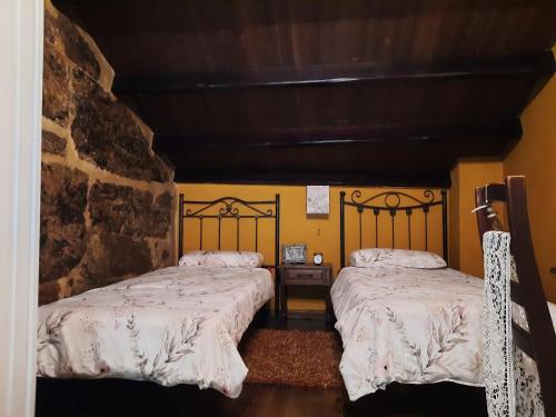 Duas camas num quarto com paredes amarelas em Casa Rural Cabo de Aráns em Oroso