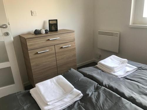 a bedroom with a bed and a dresser with towels at Pogánykő Vendégház 2 in Pákozd