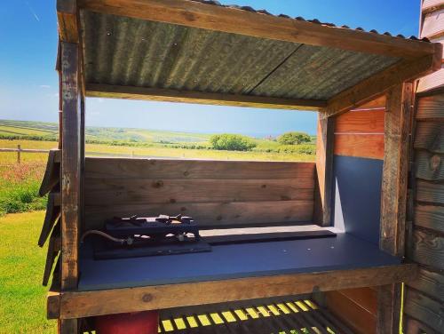 a view from inside a wooden outhouse with a window at Shepherds Hut in a private meadow with sea views in Hartland