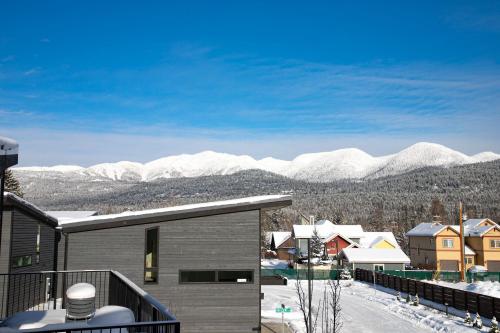 a house with a balcony with snowy mountains in the background at LUX Modern Chalet, Pool & Hot Tub, 10 Mins to the Mountain & Incredible Views in Whitefish