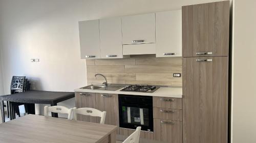 a kitchen with white cabinets and a table with chairs at House Relax Marzamemi in Noto