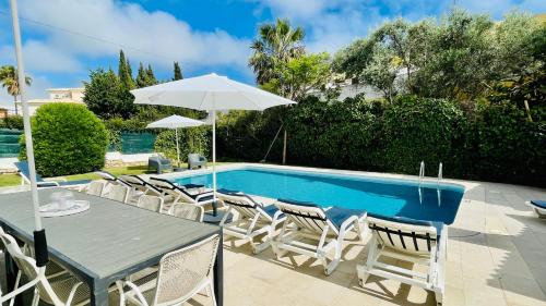 a table with an umbrella and chairs next to a pool at Strip - Private Pool - 12 Guests - Albufeira in Albufeira