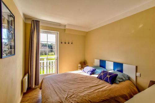 une chambre avec un lit avec des oreillers bleus et une fenêtre dans l'établissement Très jolie maison sur golf proche mer, à Talmont-Saint-Hilaire