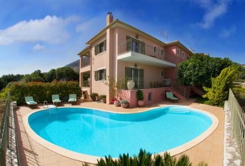 a villa with a swimming pool in front of a house at Stamoulis Villas in Ayia Evfimia