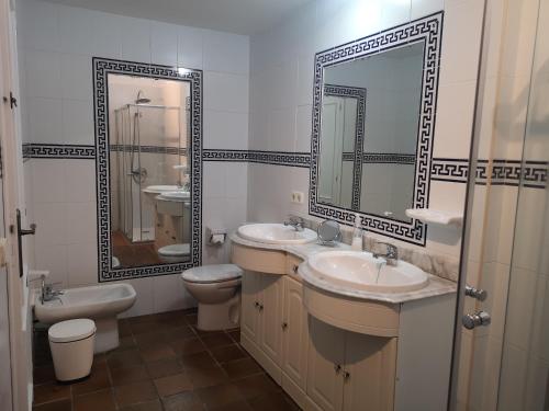 un bagno con due lavandini, servizi igienici e due specchi di toni's apartament Menorca a Cala'n Bosch