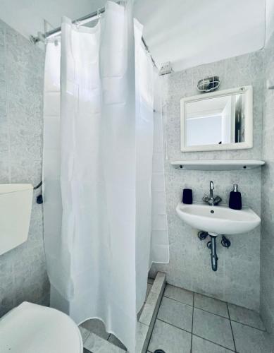 a white bathroom with a toilet and a sink at Eviamar in Loutra Edipsou