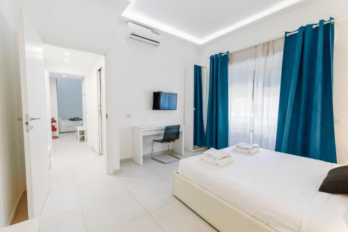 een witte slaapkamer met blauwe gordijnen en een bed bij Appartamento 21 in Milaan