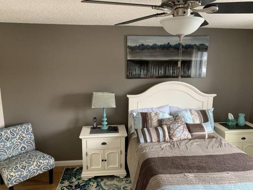 a bedroom with a bed and a chair and a ceiling fan at Chris Cozy Condo Commonwealth #205 Edmonton in Edmonton
