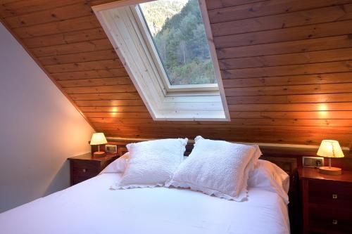 Schlafzimmer mit einem weißen Bett und einem Fenster in der Unterkunft Apartaments la Peguera in Bohí