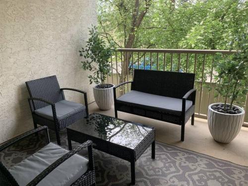 a porch with two chairs and a table and a couch at Chris Cozy Condo Commonwealth #205 Edmonton in Edmonton
