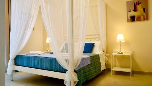 La Corte di Leuca Residence & SPA في ليوكا: غرفة نوم مع سرير المظلة مع الستائر
