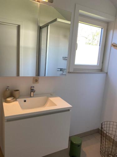 a white bathroom with a sink and a mirror at Westerhuisje in Middelkerke
