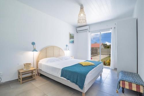 um quarto com uma cama e uma grande janela em Villa Bel'Amandier : 3ch, bac à punch à 2min à pied de la plage em Sainte-Luce