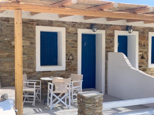 a patio with blue doors and chairs on a stone wall at Spiti Apartment in Mylopotas