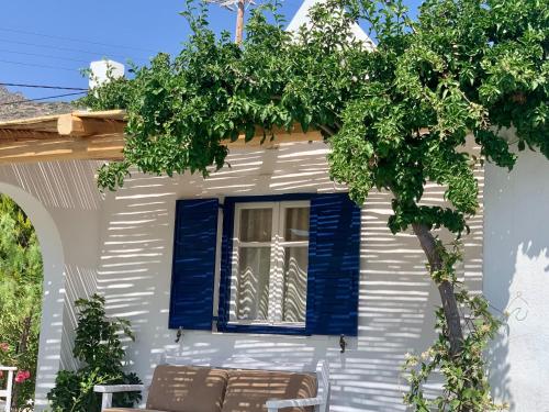 una casa con persiane blu e un albero di Spiti Apartment a Mylopotas