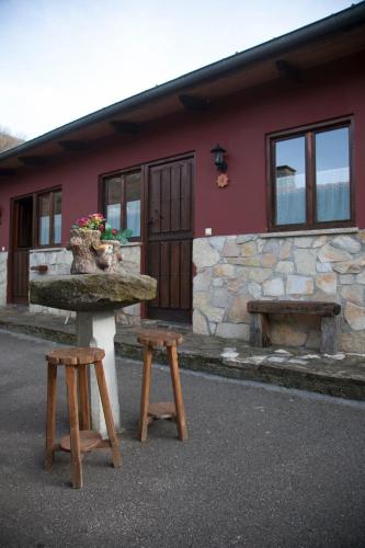 a table and two stools in front of a building at Apartamentos El Campal in Felechosa