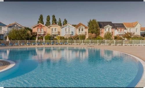 une grande piscine bleue en face de certaines maisons dans l'établissement Très jolie maison sur golf proche mer, à Talmont-Saint-Hilaire
