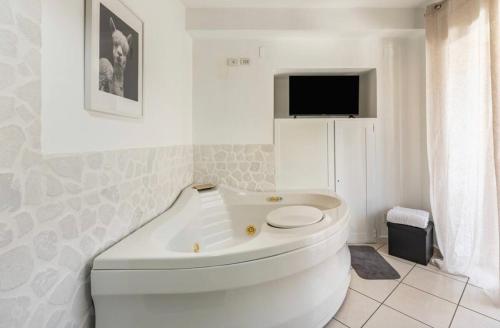 a white bath tub in a bathroom with a tv at B&B Civico 8 in Pompei
