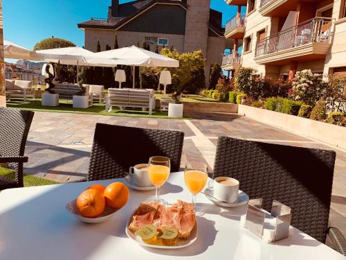 una mesa con un plato de comida y dos vasos de zumo de naranja en Hostal Esperanza del Mar, en Portonovo