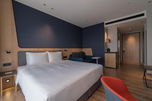 a bedroom with a large white bed and a blue wall at Holiday Inn Express Chiayi by IHG in Chiayi City