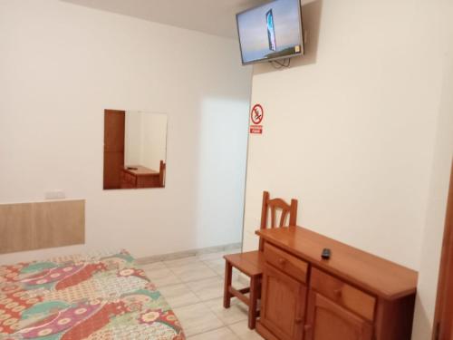 1 dormitorio con 1 cama y TV en la pared en ALOJAMIENTO PLAYA CHICA, LOS POZOS HABITACIONES en Puerto del Rosario