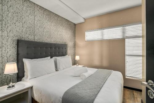 a bedroom with a large white bed and a window at Easy Stay - The Vantage Rosebank in Johannesburg